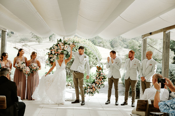 Bride and Groom twirling at ceremony under flower arbour for Brisbane Wedding